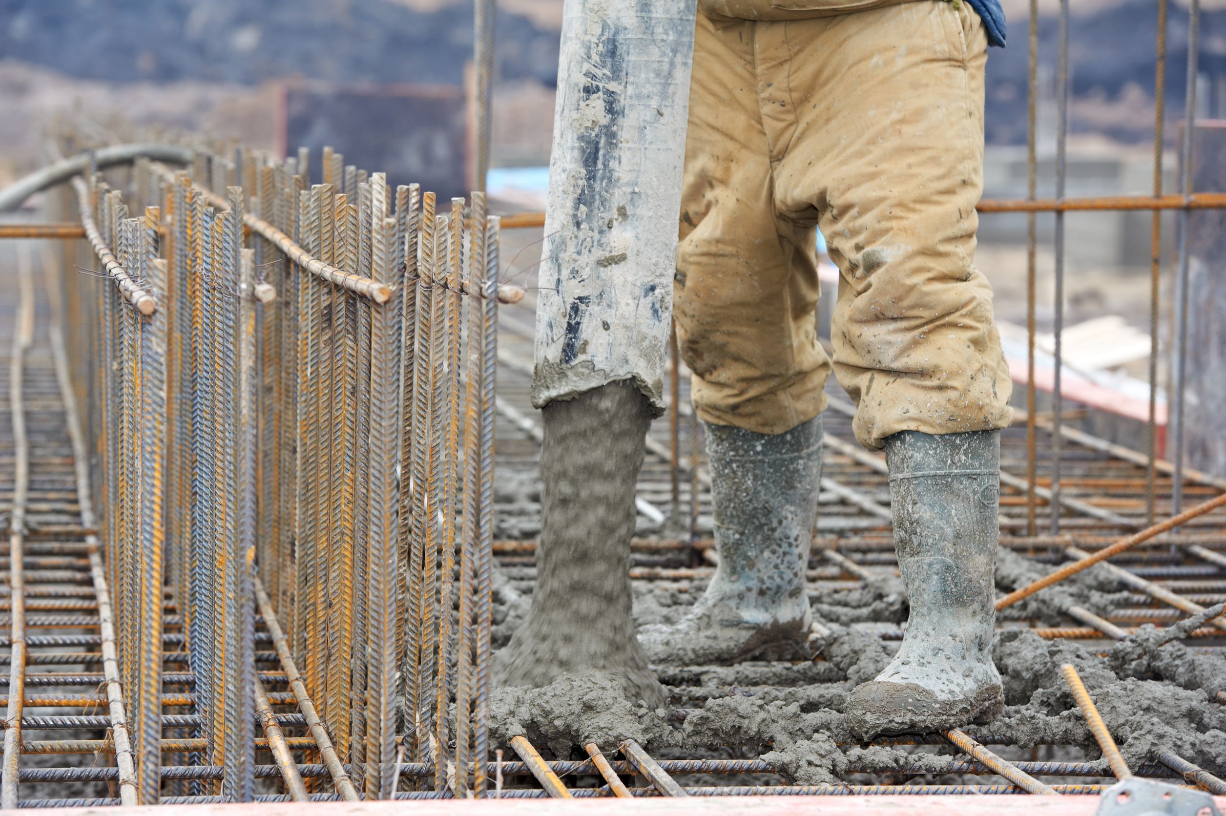 person with boots in construction site pouring concrete